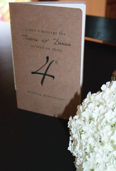 a bouquet of white flowers sitting on top of a table next to a wedding card