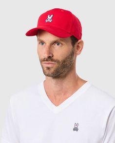 A person wearing the Psycho Bunny MENS CLASSIC BASEBALL CAP (B6A816A1HT) in red cotton twill with an adjustable fit, featuring a white rabbit skull logo, perfectly matches their white V-neck T-shirt with the same design against a simple light gray backdrop. Embroidered Bunny, Bunny Logo, The Best Outfits, Best Accessories, Best Outfits, Out Of Style, Cotton Twill, Style Guides, The Man