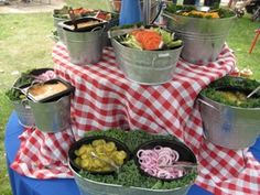 several buckets filled with food sitting on top of a table covered in red and white checkered cloth