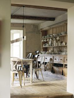 an open kitchen and dining room area with wooden flooring, white walls and cabinets