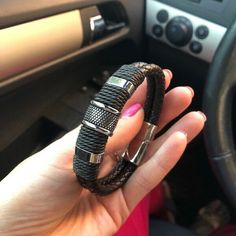 a woman is holding two bracelets in her hand while she sits in the driver's seat of a car