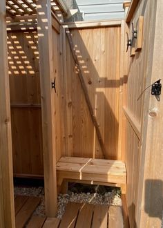 an outdoor shower with wooden steps leading to the door and side walk in area that is made out of wood planks