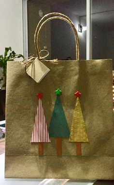 a brown paper bag with christmas trees on the front and sides, sitting on a table