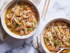 two bowls of soup with chopsticks on a marble countertop next to each other