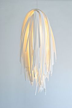 a white light hanging from a ceiling fixture with fringes on it's sides