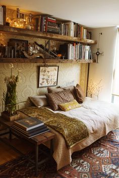 a bed sitting in the middle of a room with lots of books on top of it