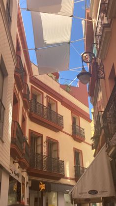 an alleyway with several buildings and balconies on the sides, under a blue sky