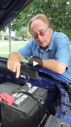 a man is working on an electrical device in the trunk of a car while looking at it