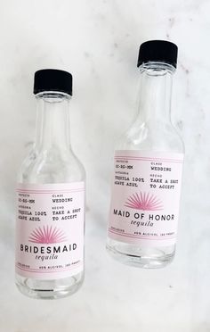 two small bottles with labels on them sitting on a marble countertop next to each other