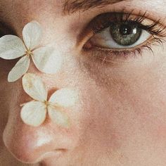 a close up of a person with flowers on their face and eyeliners in the shape of four petals