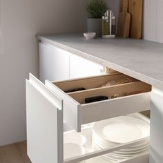 an open drawer in a kitchen with plates and utensils