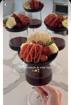 a person holding a wine glass filled with red wine and assorted appetizers