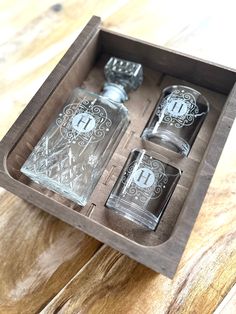 an empty bottle and two shot glasses in a wooden box