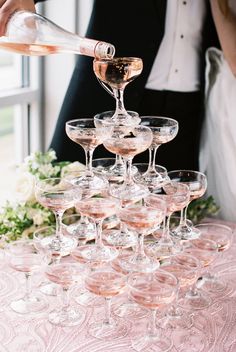 a bride and groom are pouring champagne into wine glasses for the guests to take home