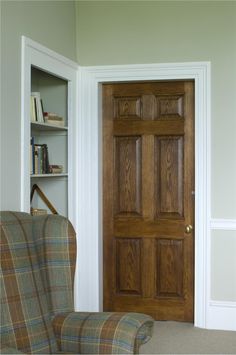 a living room with a chair, book shelf and door to another room in the background