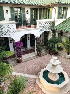 an outdoor courtyard with a fountain and potted plants