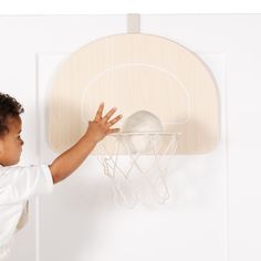 a young boy is playing with a basketball hoop on the side of a white wall