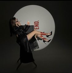 a woman in black dress and high heeled shoes standing next to a white sign