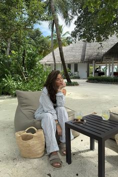 a woman sitting on top of a couch next to a table with drinks in it