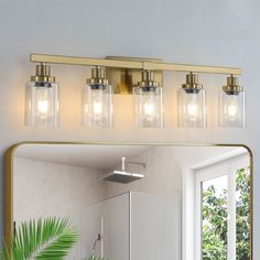 a bathroom vanity with three lights and a mirror in front of the light fixture on the wall