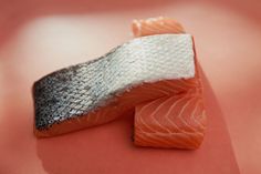 two pieces of salmon sitting on top of a pink surface with white flecks