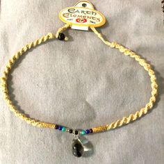 a bracelet with a stone and bead on the end is sitting on a white cloth