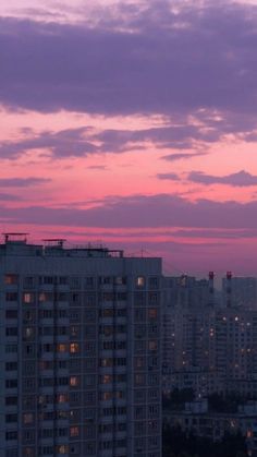 the sky is pink and purple with buildings in the background