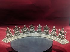 a group of buddha figurines sitting on top of a black table next to a red cloth