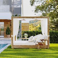 a bed sitting in the middle of a lush green field next to a swimming pool