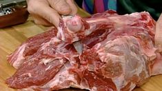 a person cutting up some meat on a wooden table