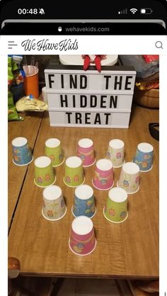 a wooden table topped with paper cups and a sign that says find the hidden treat