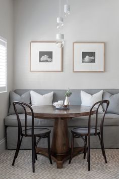 a living room with two couches and a table in the middle, along with pictures on the wall