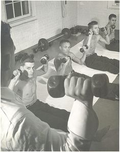 black and white photograph of men doing exercises with dumbbells