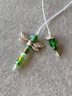 two necklaces with green and yellow beads on a white cord next to each other