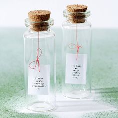 two glass bottles with labels on them sitting on a table