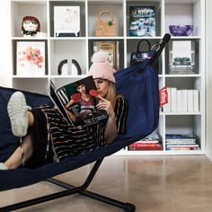 a woman laying in a chair reading a magazine