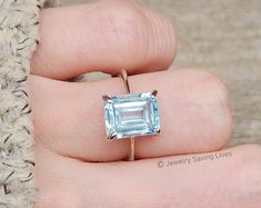 a person's hand holding a ring with an aqua blue topazte