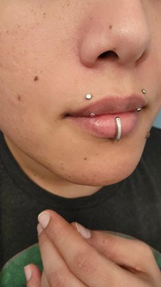 a woman with piercings on her nose holding a cup