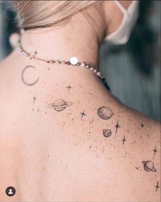 the back of a woman's neck with planets and stars tattooed on her left shoulder