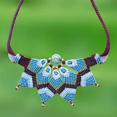 a beaded necklace is hanging from a string on a green and purple background with beads