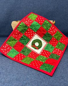 a red and green quilted table topper on a blue couch