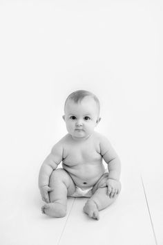 a black and white photo of a baby sitting on the floor