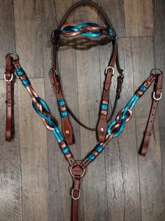 a bridle with blue and brown trimmings is on the wooden floor