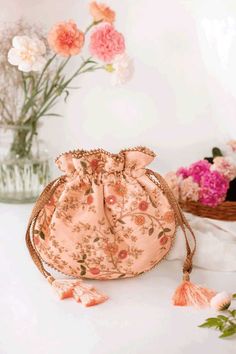 a pink flowered purse sitting on top of a white table next to some flowers