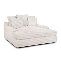 a white couch with four pillows on it's back and one arm facing the camera