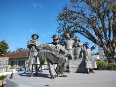 a statue of three men sitting next to each other on top of a cement slab