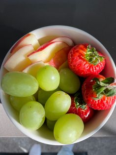 a bowl filled with grapes, apples and strawberries