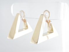 These fancy modern dangle earrings are finished in 14 karat yellow gold. They are secured by an omega closure and face forward for a good view of the triangle design from the side view. The triangles have lovely open spaces at the closure, existing as a design element as well as a functional space for wearing them.Composition: 14 Karat Yellow GoldGeneral Characteristics:Measurements: 1.5 inches x 8.19 mmTotal Gram Weight: 19.6Era: Modern 1970-PresentInscription: 14 KT--ALL PIECES ARE SUBJECT TO Modern Yellow Gold Clip-on Earrings With Polished Finish, Modern Yellow Gold Dangle Huggie Earrings, Modern Yellow Gold Clip-on Earrings For Anniversary, Modern 14k Gold Clip-on Earrings, Modern Clip-on Huggie Earrings, Modern 14k Gold Dangle Hoop Earrings, Modern Hallmarked Huggie Earrings, Modern Yellow Gold Drop Clip-on Earrings, Formal 14k Gold Dangle Huggie Earrings