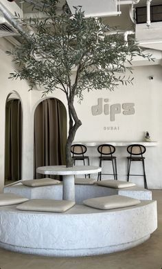 a tree in the middle of a room with tables and chairs around it that have seats on them