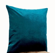 a teal blue pillow sitting on top of a wooden table next to a white wall